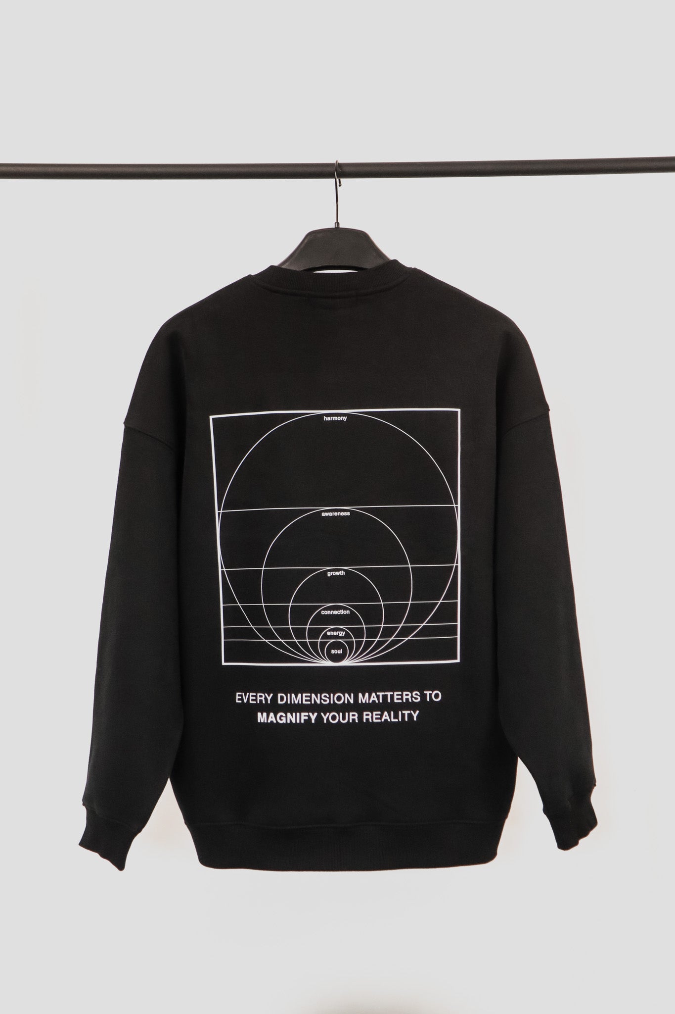 Black sweatshirt with white graphic design and text on a hanger against a light gray background