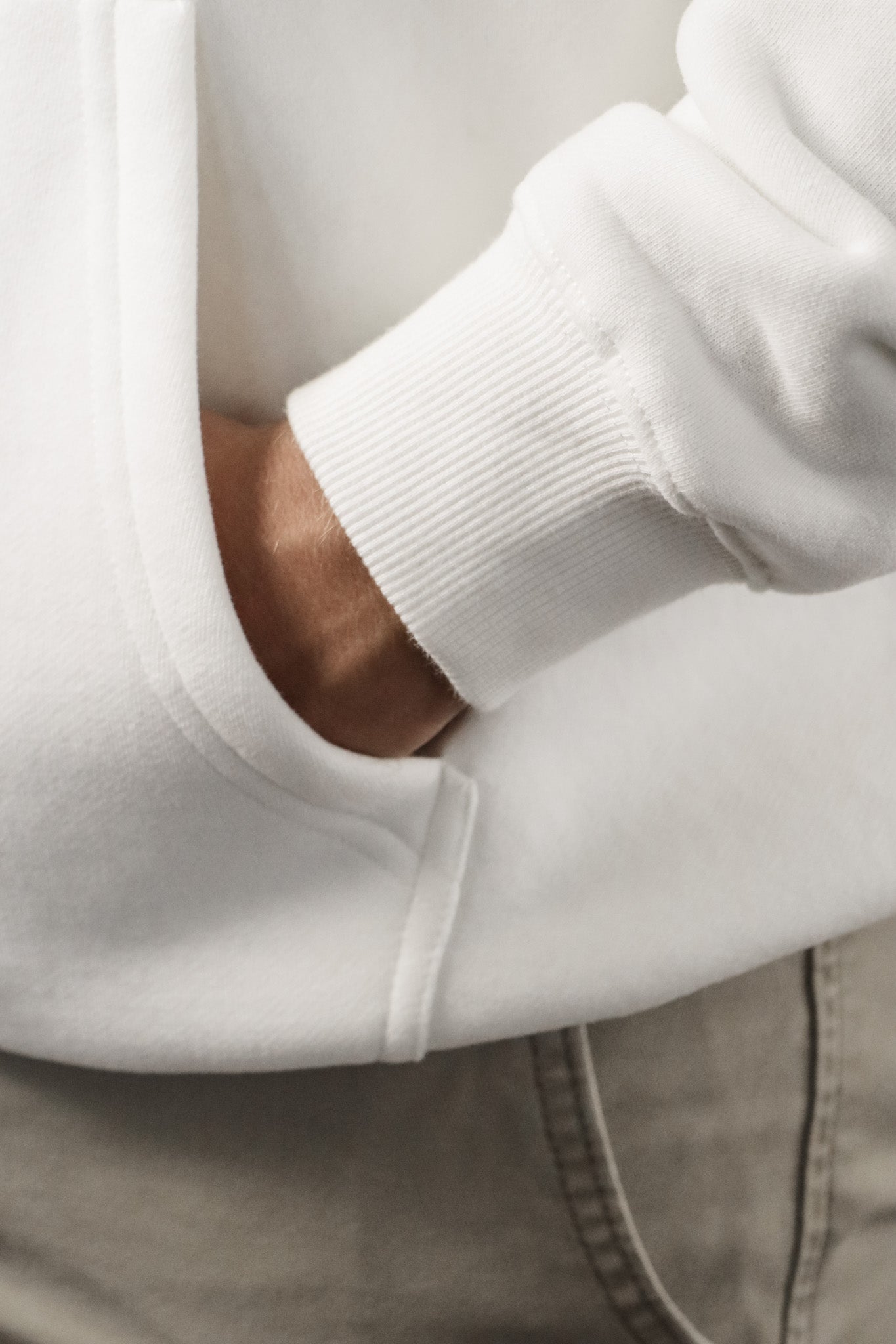Close-up of a person wearing a white sweatshirt with a neutral background