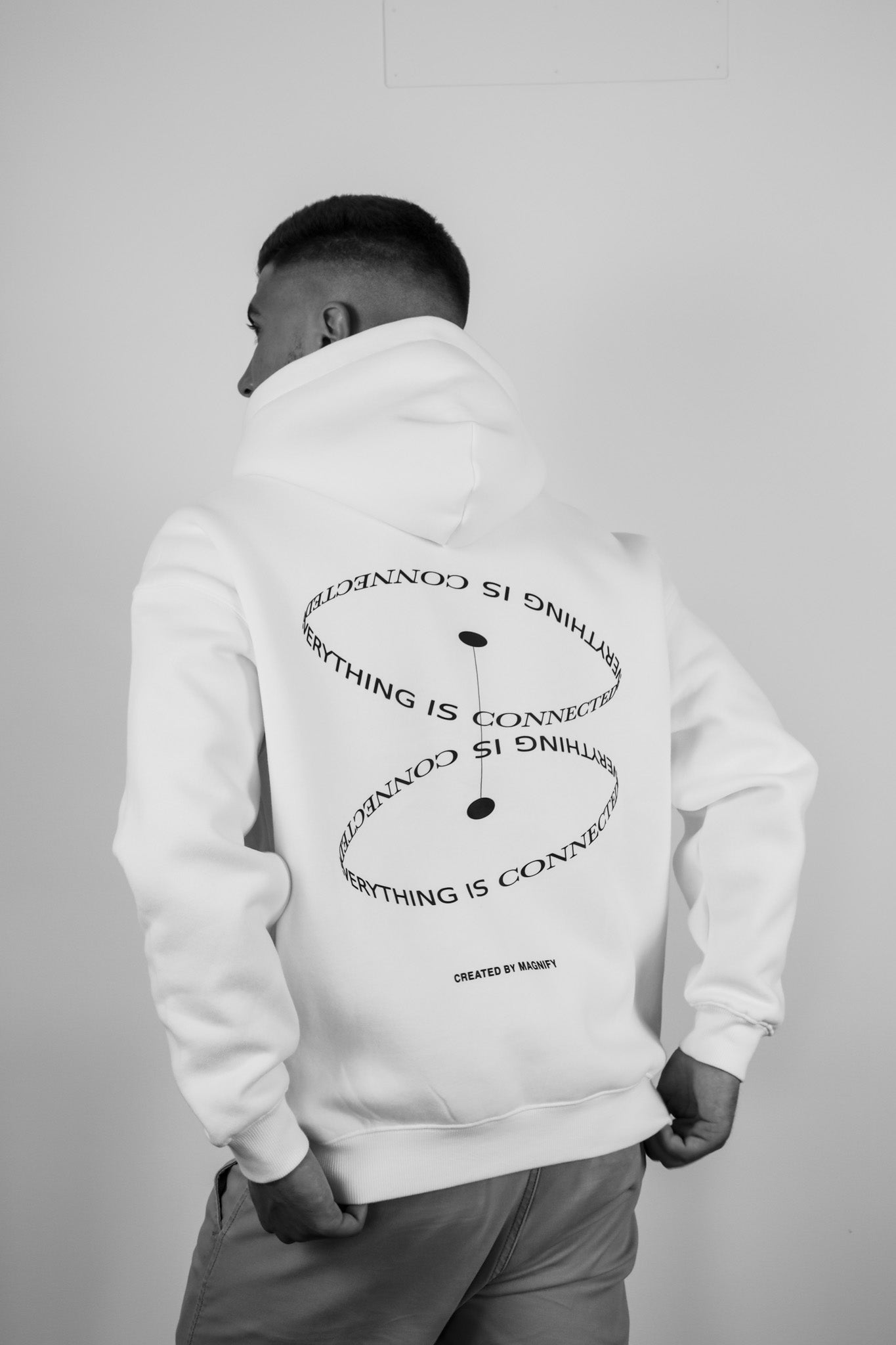 Person wearing a white hoodie with text on the back against a plain background