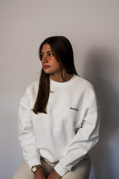 Person wearing a white sweatshirt with a logo against a plain background