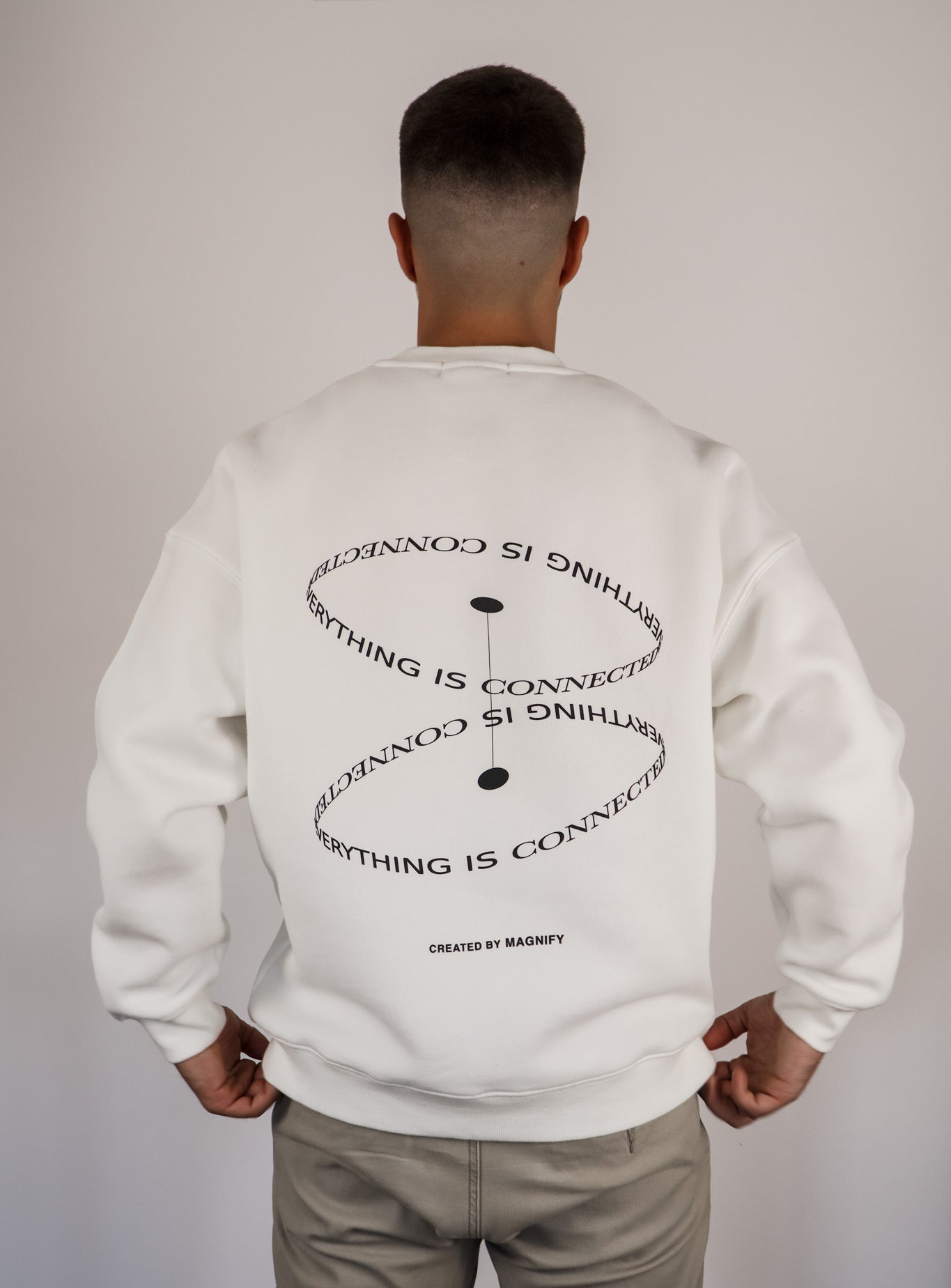 Person wearing a white sweatshirt with text on the back against a plain background