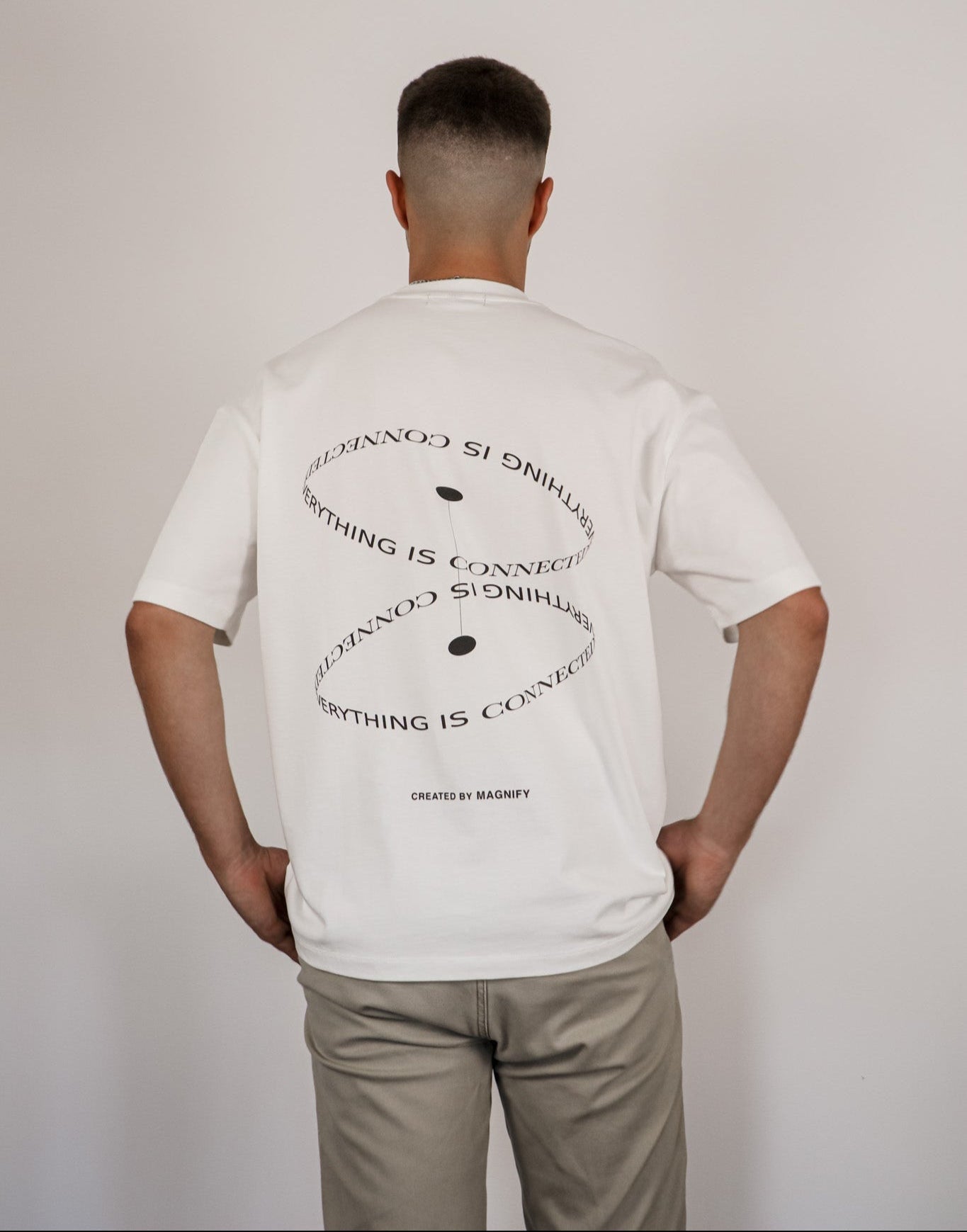 Person wearing a white t-shirt with text on the back against a plain background