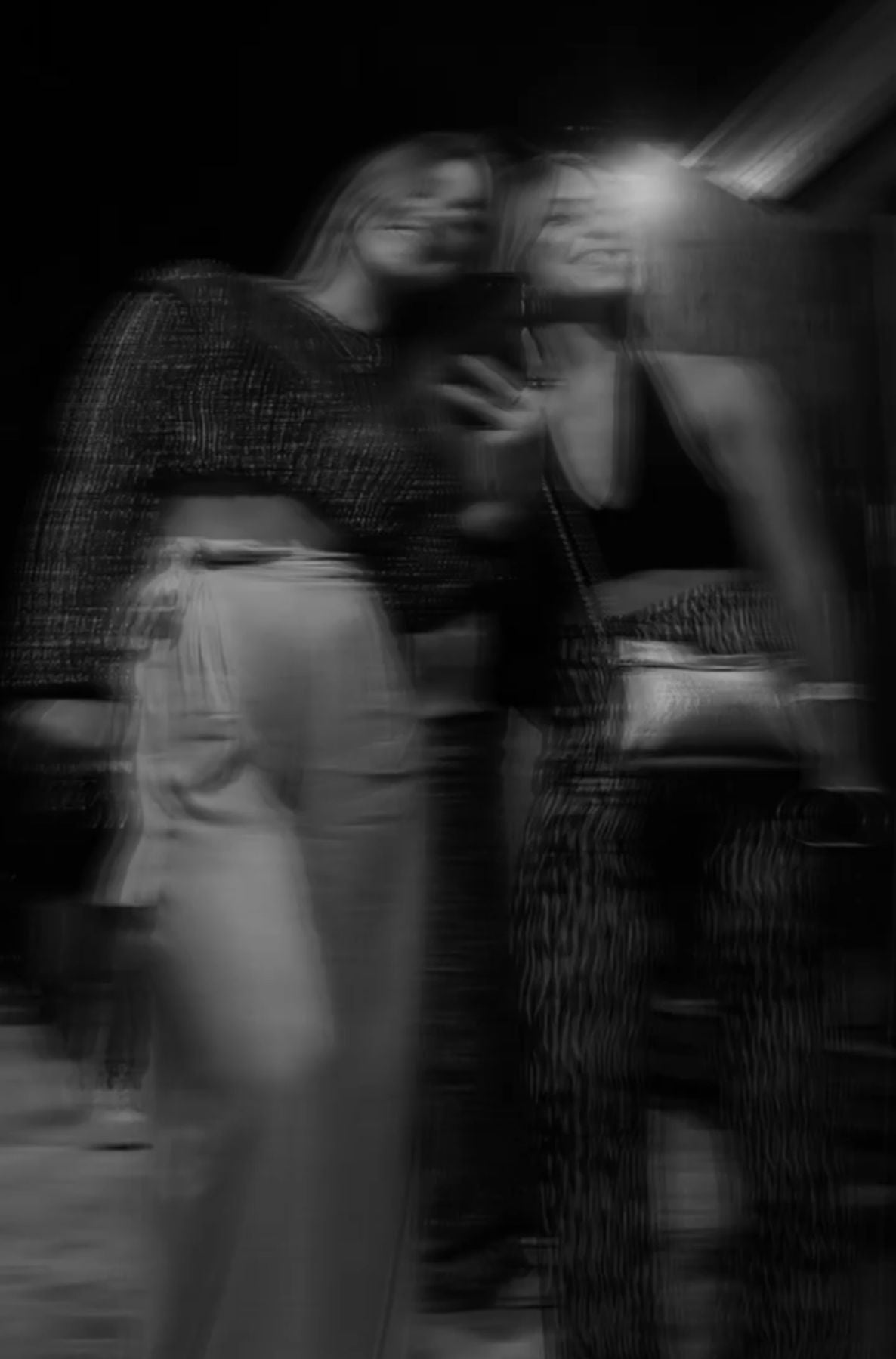 Two women taking a selfie in a mirror with a blurred background