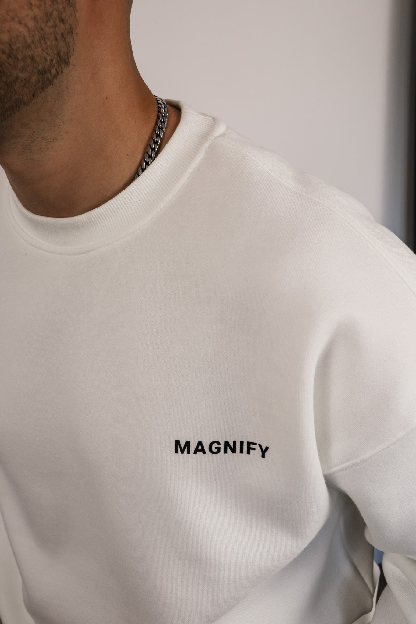 White sweatshirt with 'MAGNIFY' text on a plain background