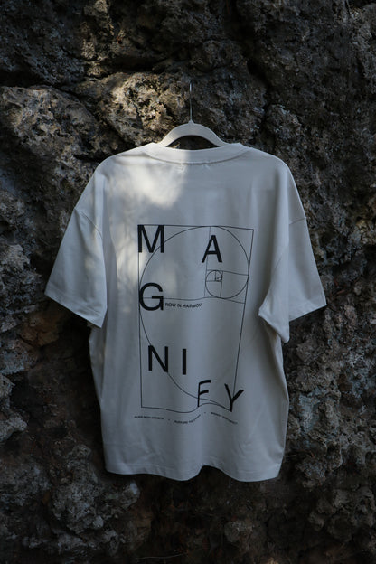 White t-shirt with black text and design on a hanger against a rocky wall
