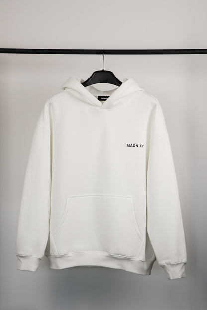 White hoodie with 'MAGNIFY' logo on a hanger against a gray background